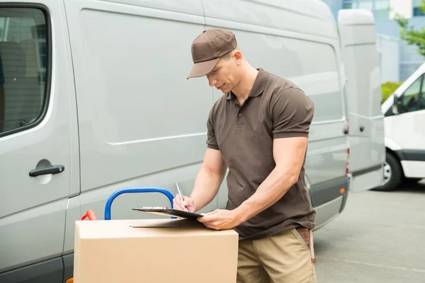 Entrega hombre escribiendo en portapapeles — Foto de Stock