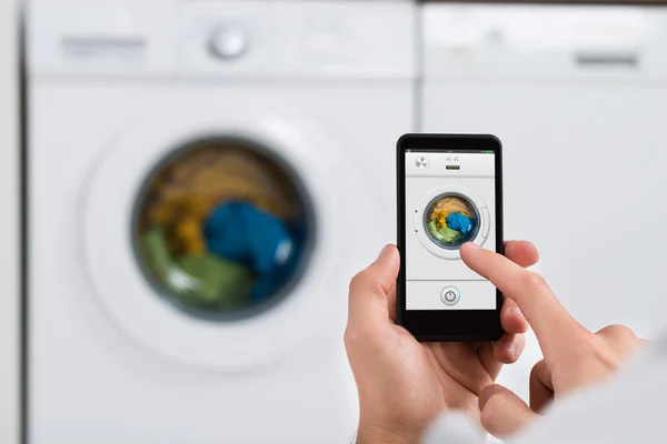 Personne avec Smartphone faisant fonctionner la machine à laver — Photo
