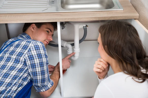 Plumber Showing Damage In Sink Pipe To Woman — Stock Photo, Image