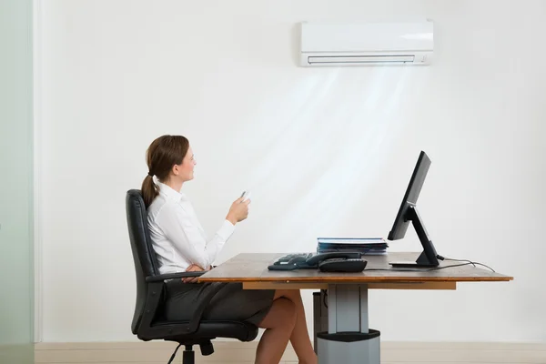 Zakenvrouw gebruik Air Conditioner — Stockfoto