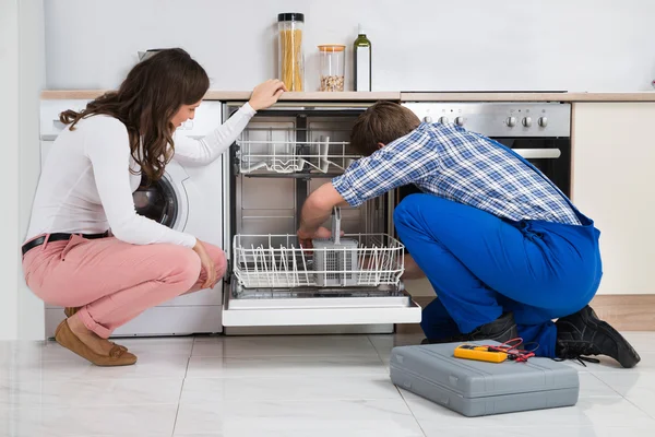 Mujer mirando reparador reparación lavavajillas — Foto de Stock