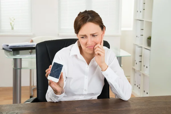 Бізнес-леді дивлячись на сломанной мобільного телефону — стокове фото