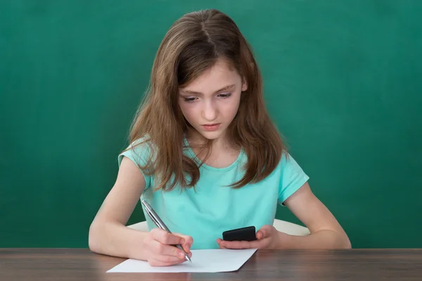 Menina com escrita de telefone móvel no papel — Fotografia de Stock