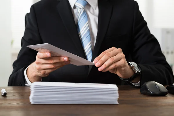 Empresário com envelopes na mesa — Fotografia de Stock