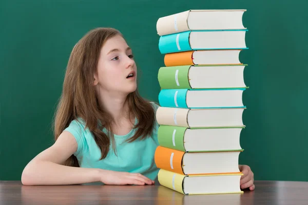 Meisje op zoek op stapel boeken — Stockfoto