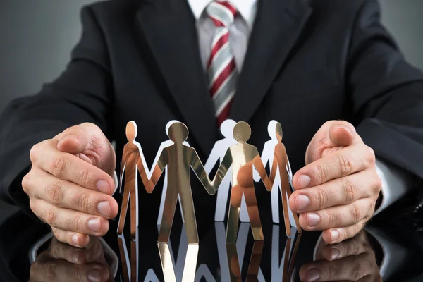 Businessperson Protecting Cutout Figures — Stock Photo, Image