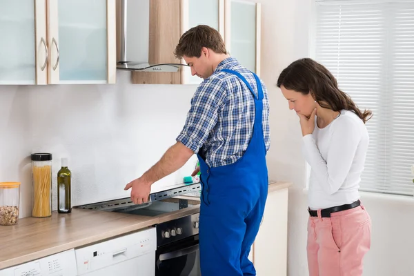 Mujer mirando trabajador reparación inducción encimera — Foto de Stock