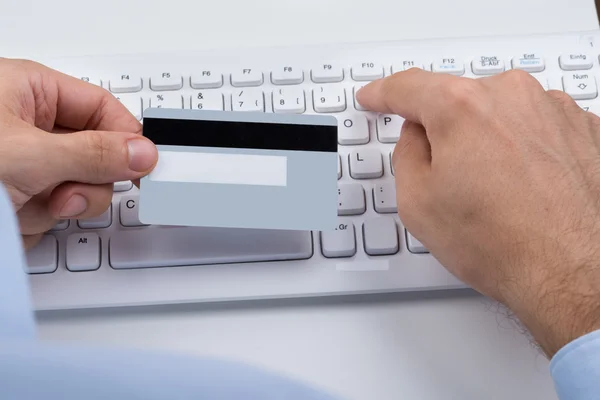 Ręce trzyma karty kredytowej na klawiaturze — Zdjęcie stockowe