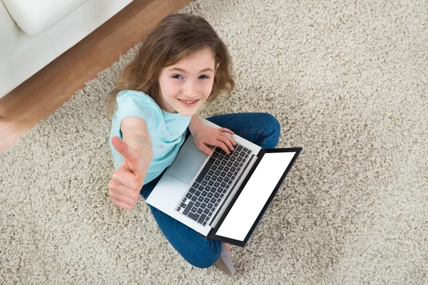 Menina sentada no tapete com laptop — Fotografia de Stock