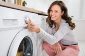 Frau drückt Taste der Waschmaschine