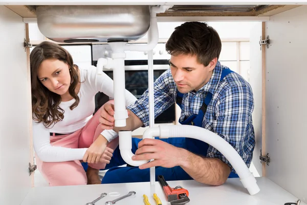 Vrouw kijken naar werknemer vaststelling van Pipe — Stockfoto