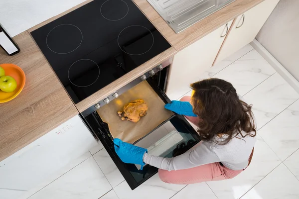 Mulher colocando bandeja com frango — Fotografia de Stock