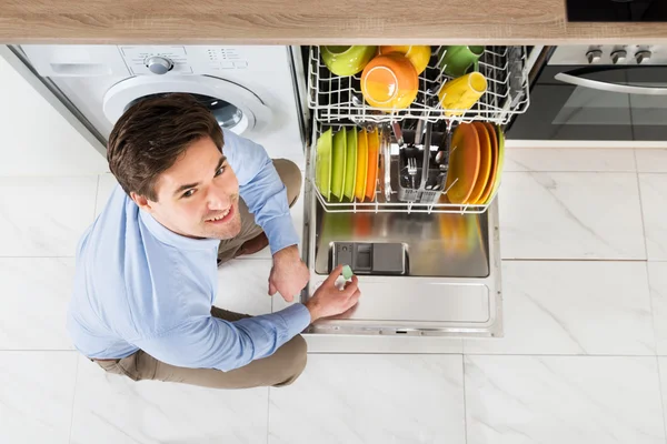 Mann setzt Spülmaschine Seifentablette ein — Stockfoto