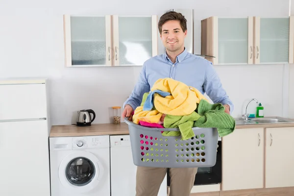 Mann trägt Korb mit Kleiderstapel — Stockfoto