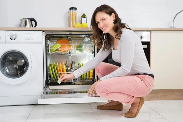 食器洗い機の洗剤タブレットを置く女性 ストック画像