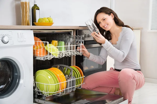 食器洗い機から飲むガラスを取っている女性 ストック写真