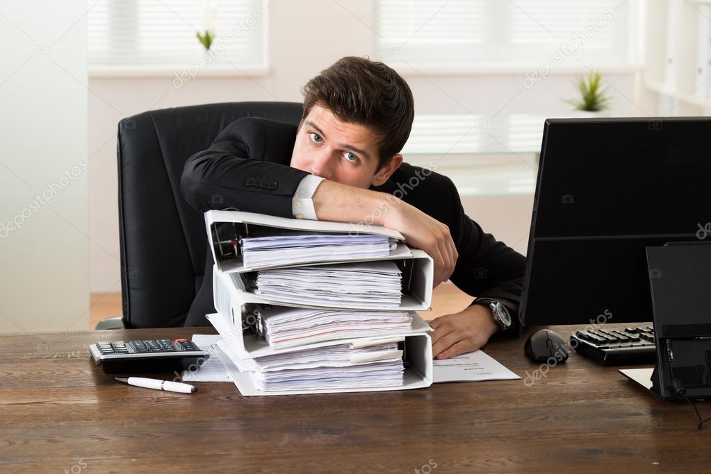 Businessman Leaning On Stack Of Folders