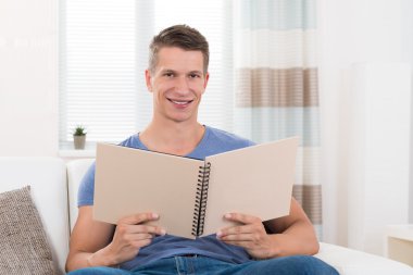 Adam kanepede oturan fotoğraf kitap ile