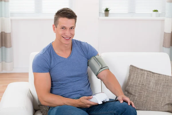 Man op Sofa controle bloeddruk — Stockfoto