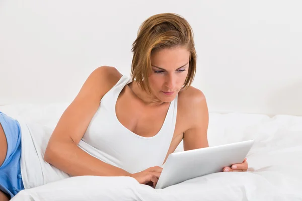 Frau im Bett mit digitalem Tablet — Stockfoto