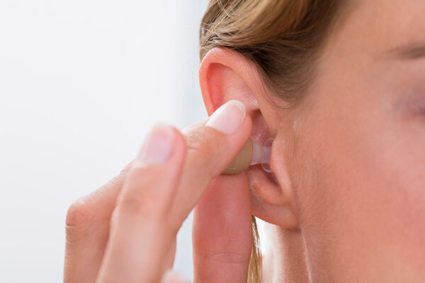 Female Hand Putting Hearing Aid In Ear