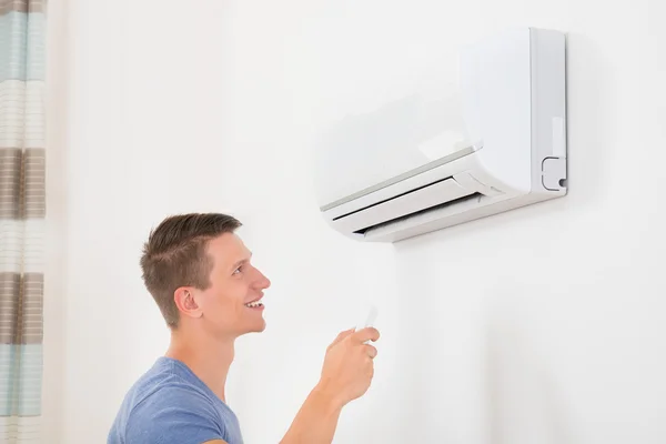 Man met de afstandsbediening van Air Conditioner — Stockfoto