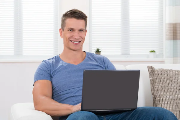 Człowiek na kanapie przy użyciu laptopa — Zdjęcie stockowe