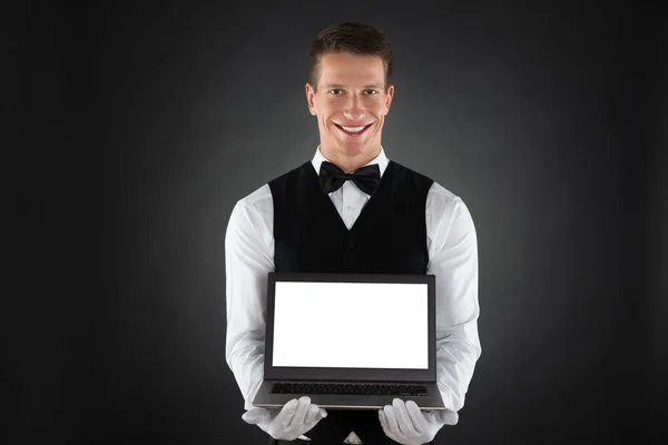Felice cameriere mostrando computer portatile — Foto Stock