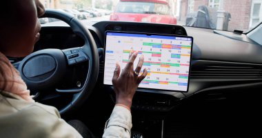 Gantt yazılımını kullanarak arabadaki programı planlayan Amerikalı kadın..