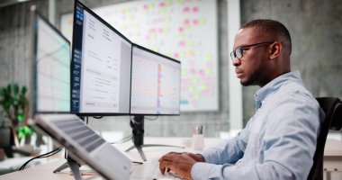 Genç Afrikalı Amerikalı Adam Birden Fazla Faturayı İncelemek İçin Bilgisayarı Kullanıyor.