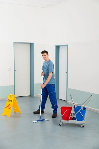 Mannelijke werknemer met het schoonmaken van uitrustingen vloer dweilen — Stockfoto