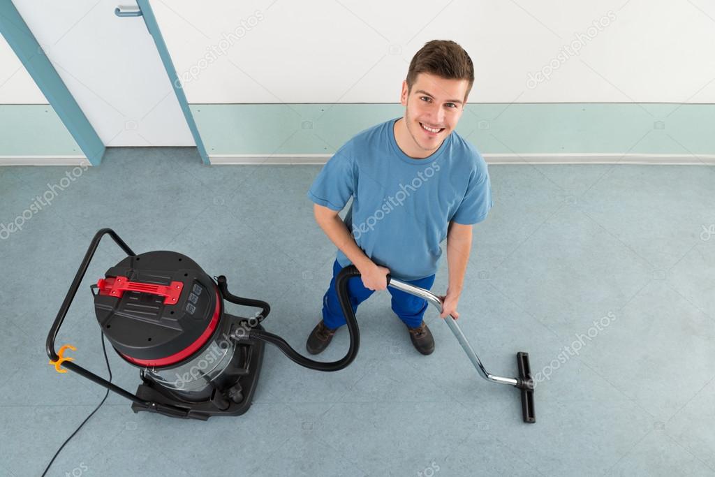 Male Cleaner Cleaning Floor With Vacuum Cleaner