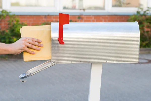 Person legt Briefe in Briefkasten — Stockfoto