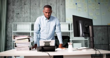 Adam ofisinde OCR yazılımı olan belgeleri tarıyor..