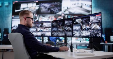 Erkek Teknisyen birden fazla ekranı izlemek için CCTV 'yi kullanıyor.