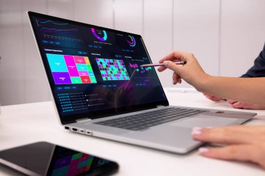 İşkadını ve İşadamı Ofisteki Dizüstü bilgisayardaki Mali Verileri Analiz Ediyor.