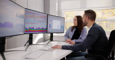 Finansal Analistler İşyerindeki Bilgisayar Kontrol Panelini kullanarak Piyasa Eğilimleri Çalışıyor.