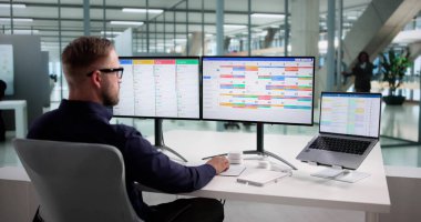 Çoklu Ekranı Çevrimiçi Olan Zamanlama ve Projeleri Düzenleyen Meşgul Adam.