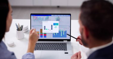 Young Data Analyst Analyzes KPI Dashboard On Computer In Office.