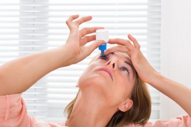 Woman Pouring Medicine Drops In Eyes clipart