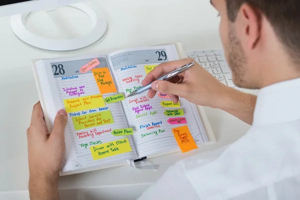 Zakenman kijkend naar de lijst van kantoorwerk — Stockfoto