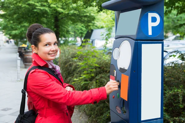 Frau steckt Münze in Parkuhr — Stockfoto