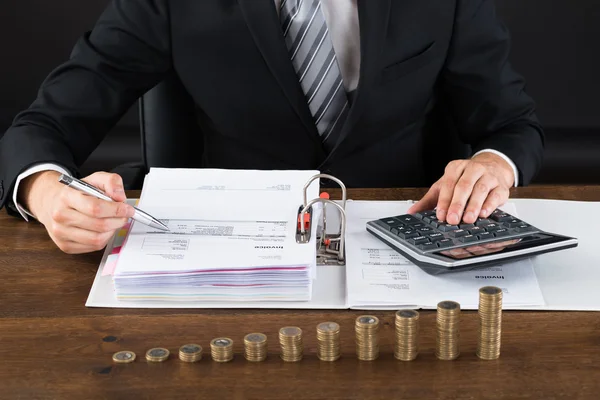 Businessman Calculating Invoice With Coins At Desk — Stock Photo, Image