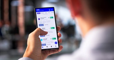 Genç İspanyol adam akıllı telefonu iş aramak ve başvurmak için kullanıyor..