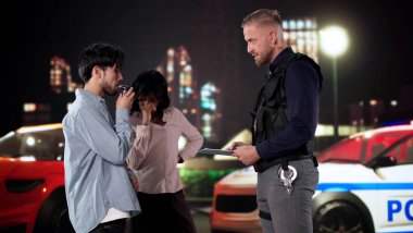 Yolcu kontrol noktasında endişeli bir şekilde izlerken sürücü alkol testi yaptırıyor.