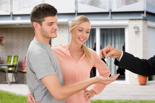 Agentin übergibt Schlüssel an junges Paar — Stockfoto