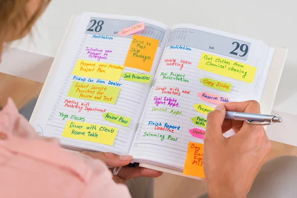 Mulher fazendo lista de trabalho de escritório no diário — Fotografia de Stock