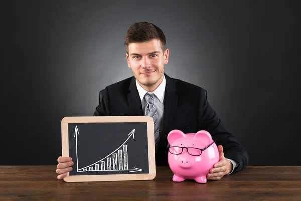 Geschäftsmann mit Sparschwein zeigt Grafik — Stockfoto