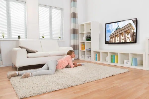 Donna sdraiata sul tappeto mentre guardava la televisione — Foto Stock