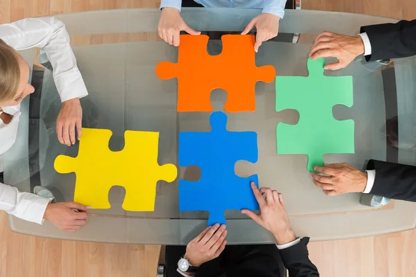 Businesspeople With Jigsaw Pieces At Desk — Stock Photo, Image